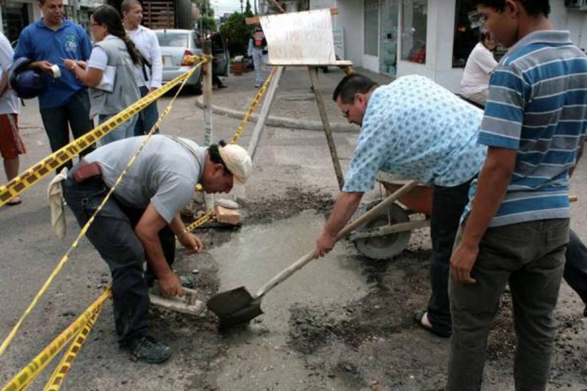 Cansados de no recibir respuesta por parte de la Secretaría de Infraestructura, los vecinos del barrio Colombia decidieron tomarse el problema en sus propias manos y arreglar algunos huecos de la calle 49, como acto simbólico.(Foto: Ricardo Pérez/VANGUARDIA LIBERAL)