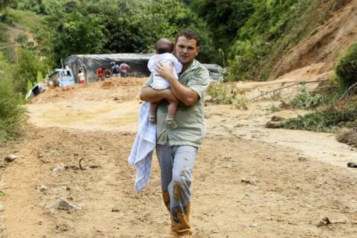 Este hombre, que lleva en sus brazos a su hija de seis meses, caminó cuatro horas para llegar hasta El Playón en busca de un medio de transporte que lo llevara a San Alberto. Como él cerca de 200 viajeros se arriesgaron a la travesía de caminar durante horas y sortear la avalancha para llegar a sus destinos. (Foto: César Flórez/VANGUARDIA LIBERAL)