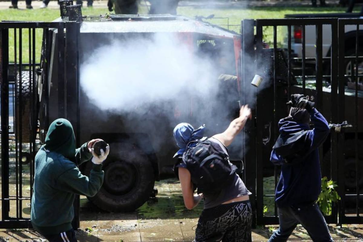Estudiantes se enfrentan a un vehículo antidisturbios durante los altercados que tuvieron lugar a la entrada de la Universidad Central en Santiago de Chile. (Foto: EFE / VANGUARDIA LIBERAL)