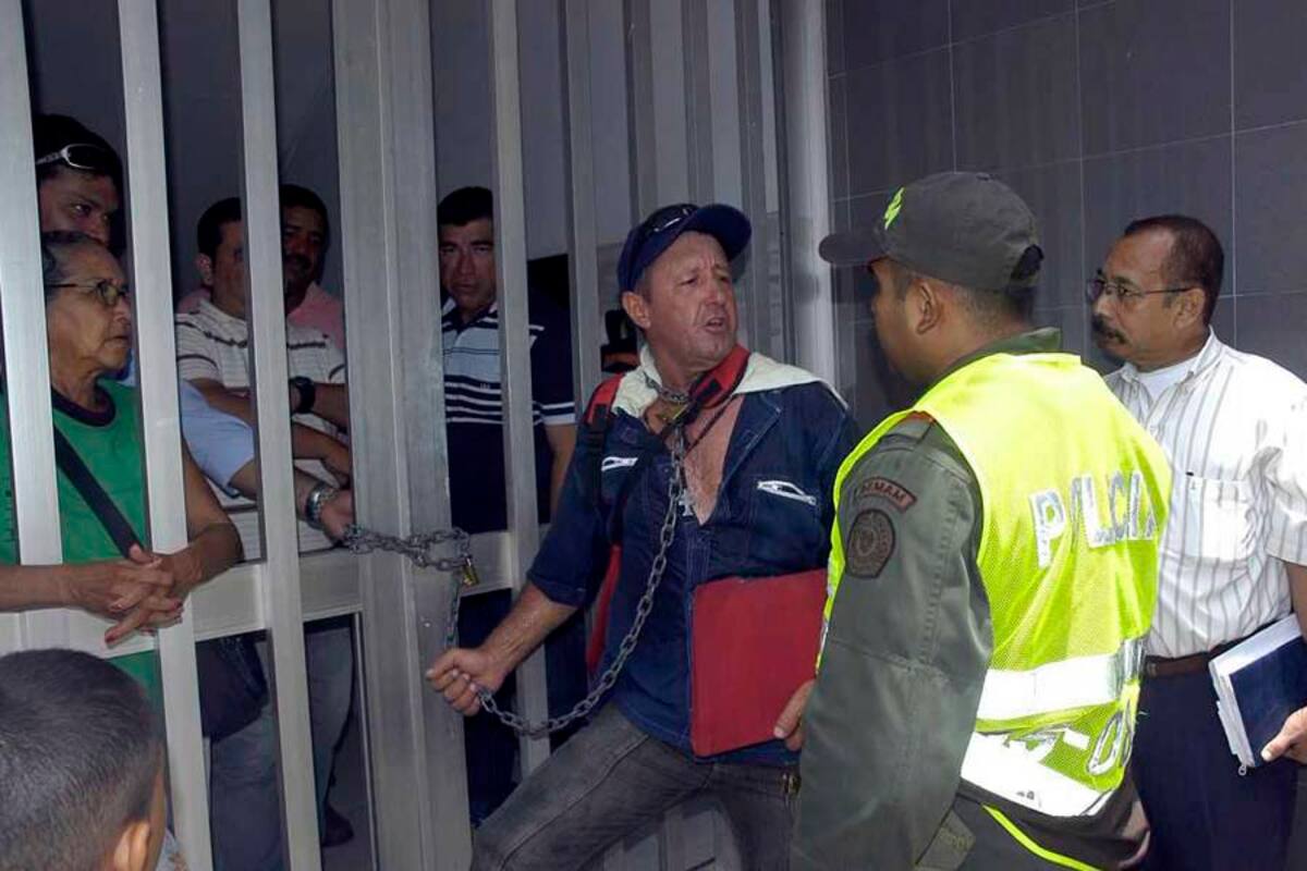 El hombre aseguró la cadena en su cuello y en las rejas del edificio donde funciona la Procuraduría, exigiendo atención a su caso. (Foto: Édgar Pernett/VANGUARDIA LIBERAL)