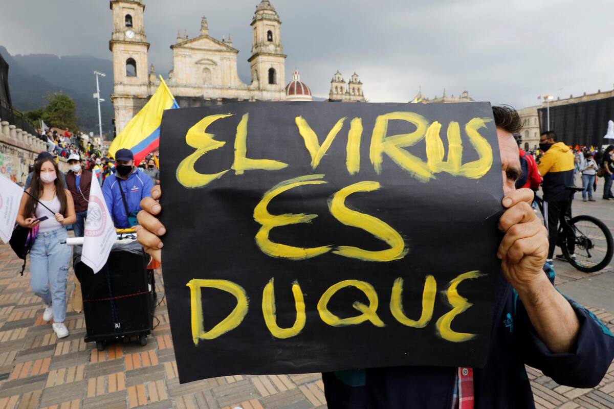 Un manifestante llega a la Plaza de Bolívar con un letrero que dice "Duque es el virus" durante una nueva jornada de protestas por un nuevo "paro nacional" convocado por los sindicatos y organizaciones sociales, que desde el pasado miércoles movilizan a miles de personas en todo el país.