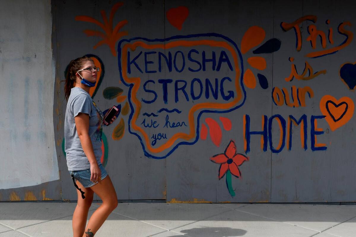 Una joven pasa junto a un mural en un edificio a raíz del tiroteo de Jacob Blake por parte de agentes de Policía, en Kenosha, estado de Wisconsin, el pasado 27 de agosto. (Foto: EFE / VANGUARDIA)