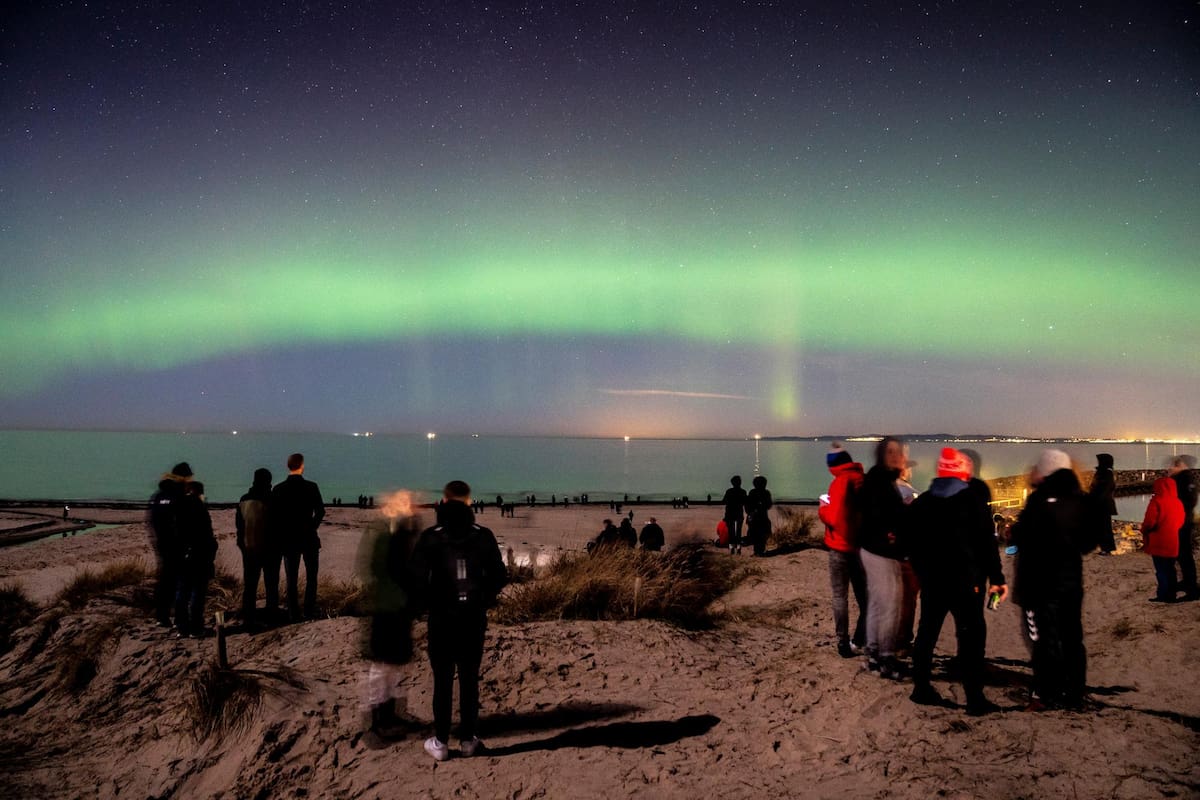 Un grupo de personas observa la aurora boreal que aparece en el cielo de Dinamarca vista desde la región e Hornbaek Strand, en el norte de Zelanda. EFE / VANGUARDIA
