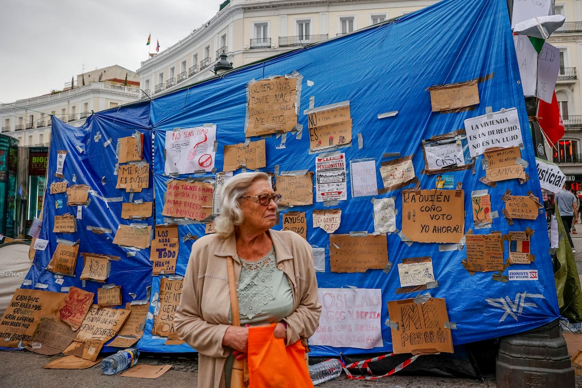 MADRID, 06/10/2026.- Una mujer junto a la acampada que permanece en la Puerta del Sol en protesta por la crisis de la vivienda, este martes, en el que el Gobierno prevé volver a aprobar los decretos en materia de vivienda para llevarlos a la Diputación Permanente. EFE/ Daniel Gonzalez