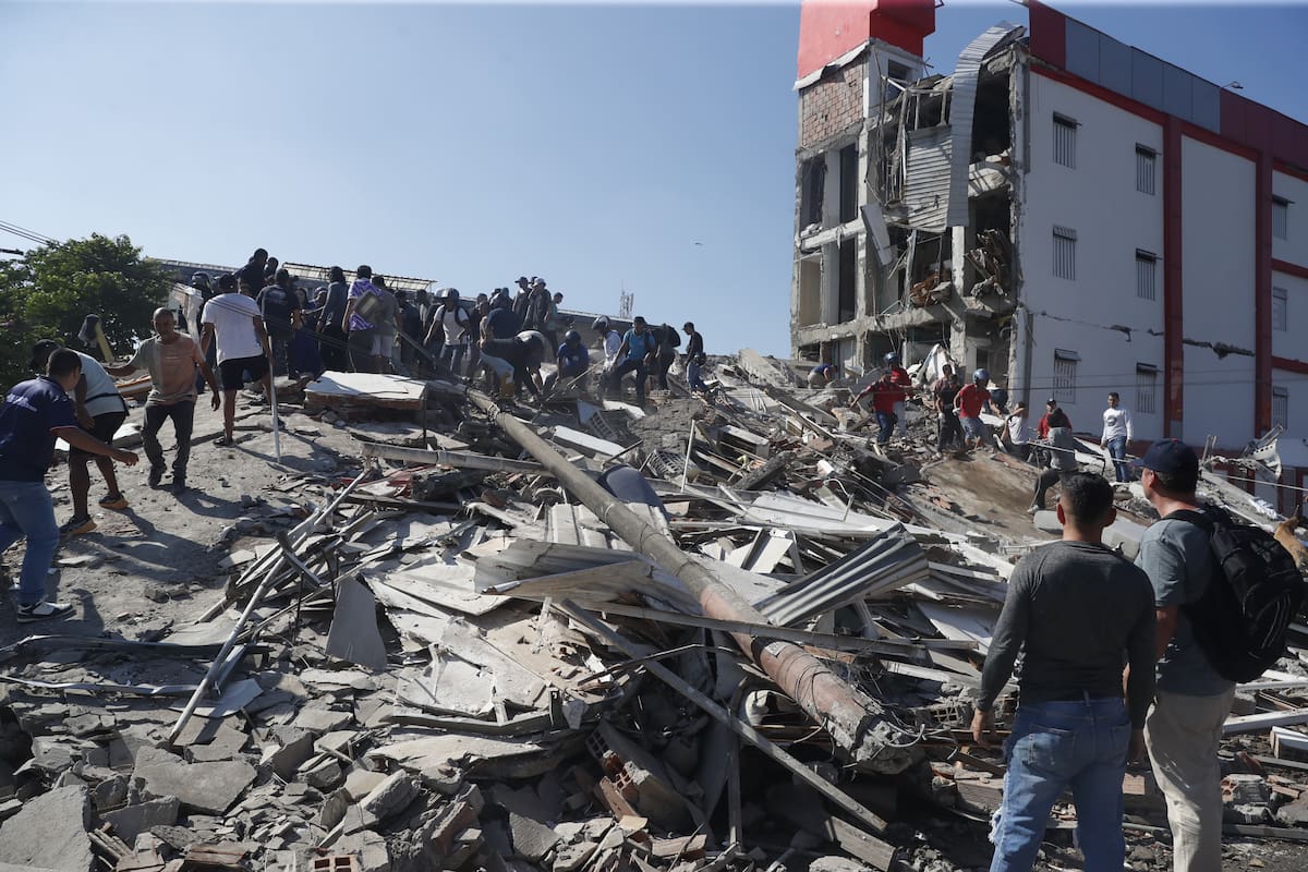 Personas caminan sobre los escombros de un edificio colapsado este lunes, en Cali (Colombia). //EFE - Ernesto Guzmán.