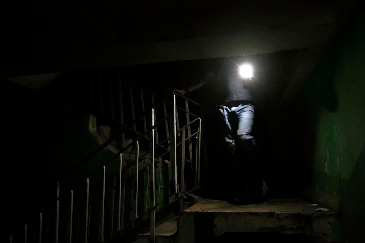 Fotografía de archivo de una persona que baja las escaleras mientras alumbra con un teléfono en La Habana (Cuba). EFE/ Ernesto Mastrascusa