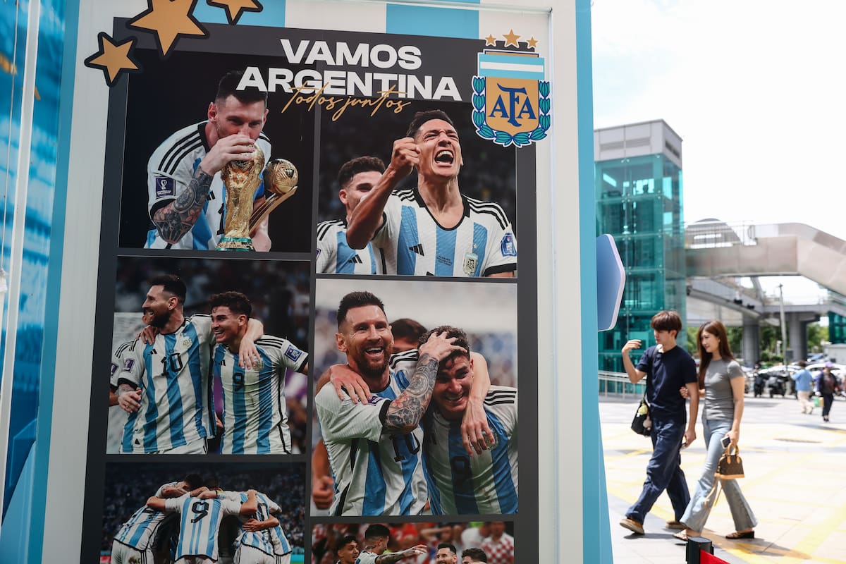 Compradores caminan junto a una pancarta con imágenes de la leyenda del fútbol argentino Lionel Messi y sus compañeros de equipo frente a una tienda oficial y autorizada de la Copa Mundial de la FIFA 2026, en Pekín, China, el 16 de julio de 2026. (Mundial de Fútbol)