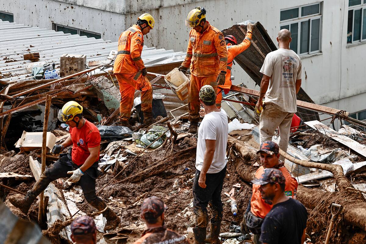 AME8302. JUIZ DE FORA (BRASIL), 25/02/2026.- Integrantes del equipo de Bomberos y voluntarios remueven escombros durante las labores de rescate en una zona afectada por fuertes lluvias este miércoles, en Juiz de Fora (Brasil). El número de víctimas mortales causado por las lluvias que azotan el sureste de Brasil aumentó a 36 en el estado de Minas Gerais, mientras que los equipos de rescate buscan a 33 desaparecidos, informaron fuentes oficiales.EFE/ Andre Coelho