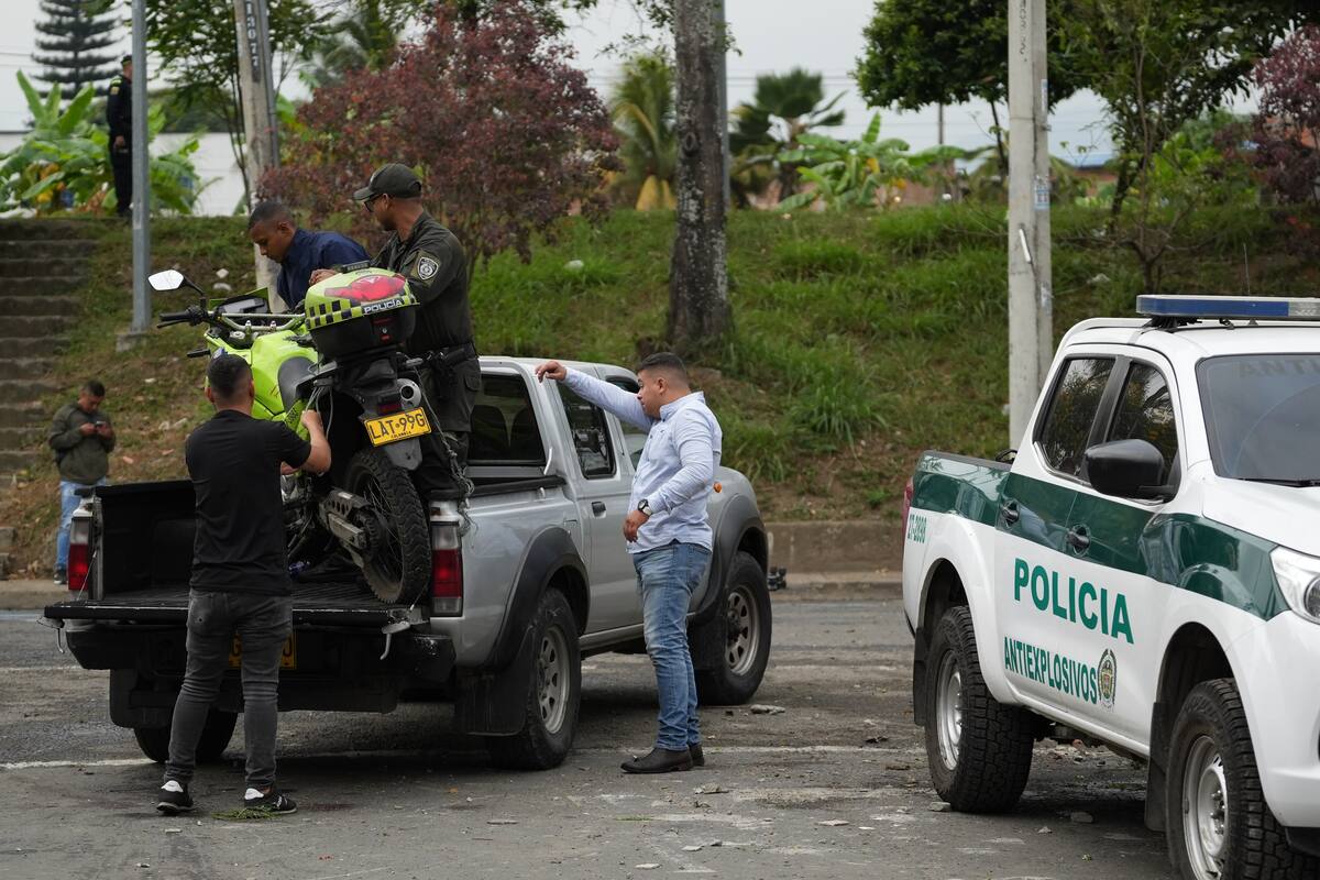 Investigadores de civil mueven la moto en la que se movilizaban dos policías que murieron luego de una explosión este martes, en Cali (Colombia). EFE/ Ernesto Guzmán