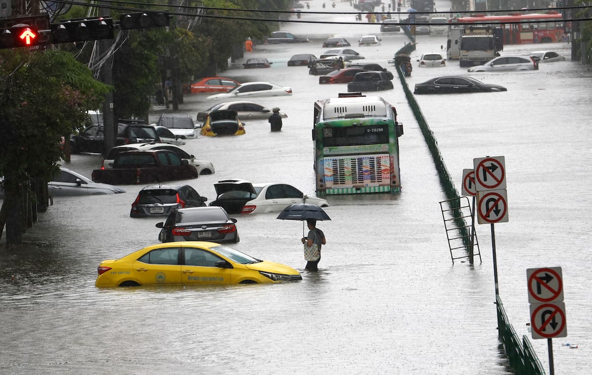Personas caminan en medio del agua mientras vehículos sumergidos quedan abandonados durante un fuerte aguacero en una vía principal inundada en Bangkok, cuyos 50 distritos han sido declarados zonas de desastre tras las intensas y persistentes lluvias provocadas por un fuerte sistema de baja presión, sumado a los patrones estacionales del monzón. EFE/EPA/RUNGROJ YONGRIT