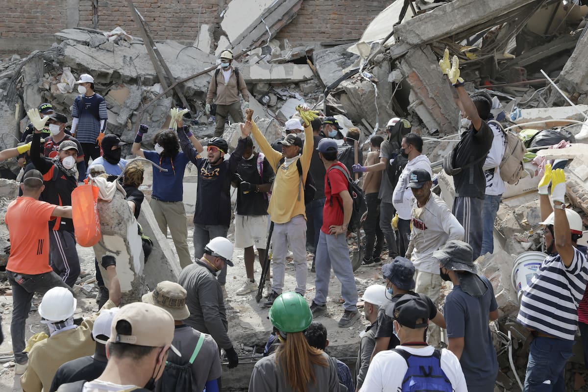 AME8355. PEREIRA (COLOMBIA), 12/08/2026.- Voluntarios levantan los brazos para pedir silencio durante las labores de búsqueda en edificaciones destruidas por el terremoto de magnitud 7,4 del pasado lunes, este miércoles en Pereira (Colombia). EFE/ Carlos Ortega