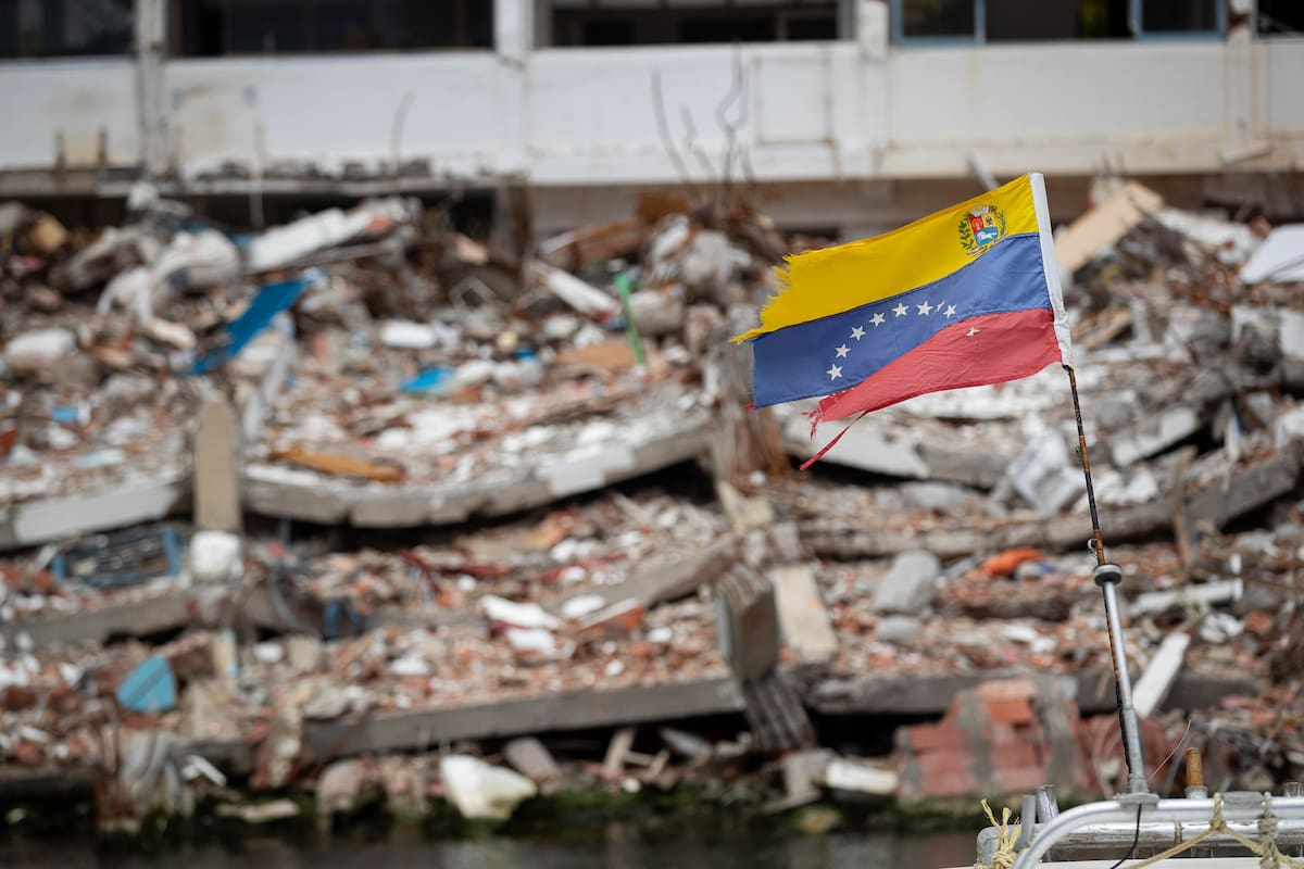 AME7458. LA GUAIRA (VENEZUELA), 09/08/2026.- Fotografía de una bandera de Venezuela frente a un edificio colapsado por los terremotos del 24 junio, este domingo en La Guaira (Venezuela). EFE/ Ronald Peña R