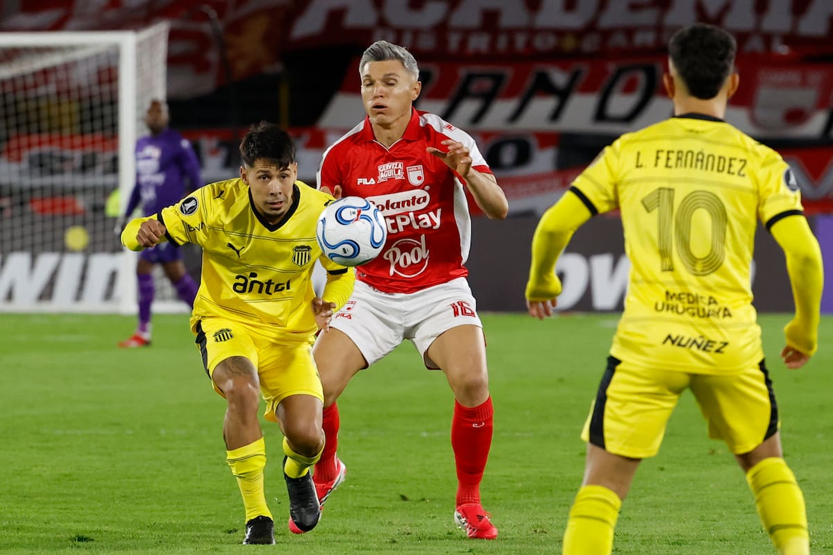 AME1962. BOGOTÁ (COLOMBIA), 09/04/2026.- Daniel Torres (c) de Santa Fe disputa el balón con Nicolás Fernández de Peñarol este jueves, en un partido de la fase de grupos de la Copa Libertadores entre Independiente Santa Fe y Peñarol este jueves, en el estadio El Campín, en Bogotá (Colombia). EFE/ Mauricio Dueñas Castañeda