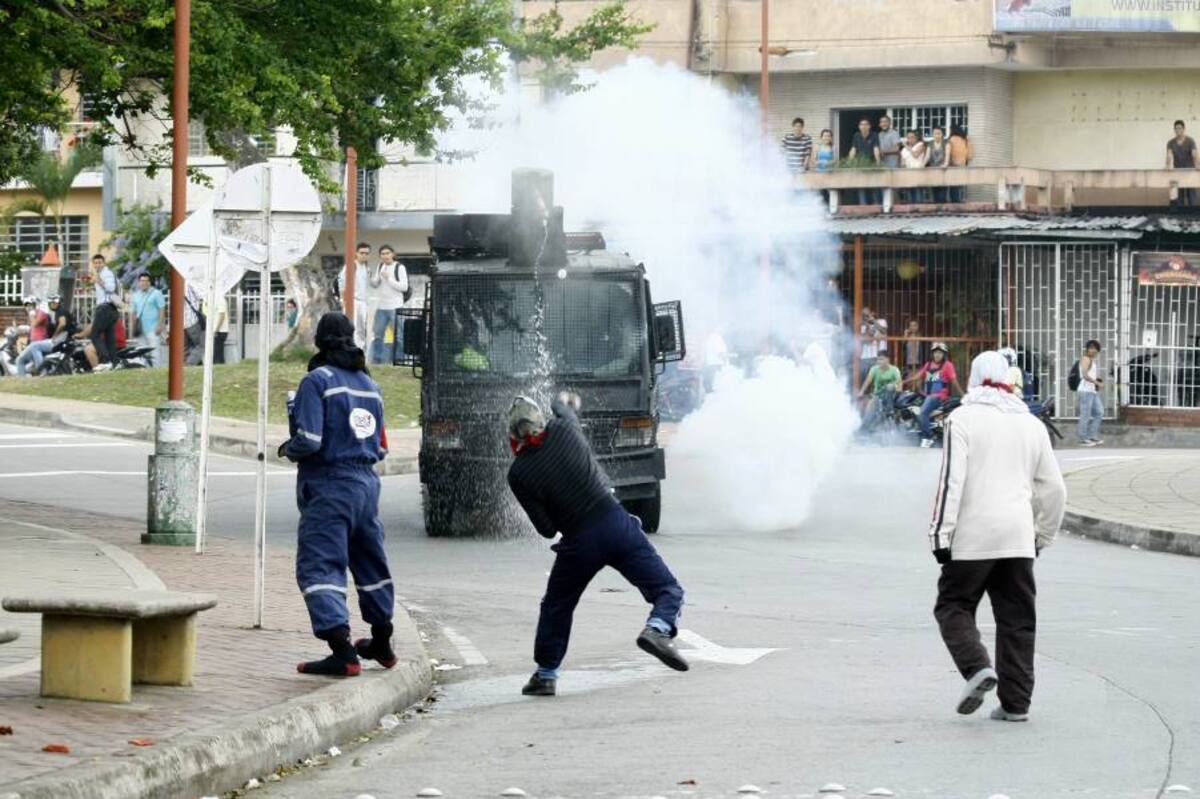En esta imagen se puede observar cómo tres encapuchados tiran ‘papas bomba’ a una tanqueta del Esmad, que le responde lanzando chorros de agua. (Foto: César Flórez / VANGUARDIA LIBERAL)