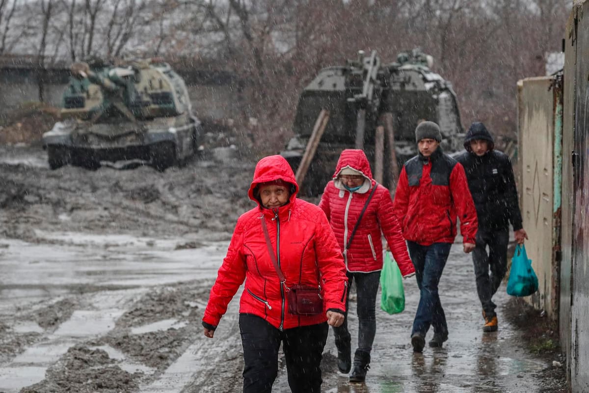 La gente camina frente a vehículos blindados rusos en la estación de tren en la región de Rostov, Rusia. FOTO/EFE