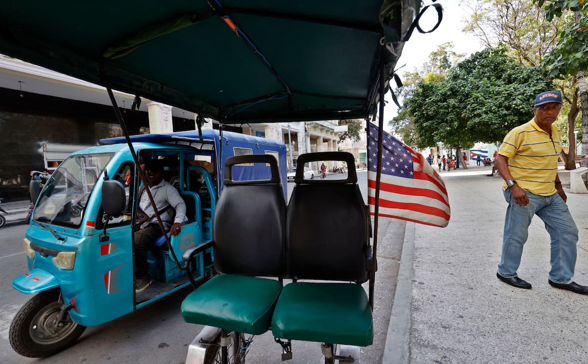 Una persona camina junto a un bicitaxi que tiene colgada la bandera de Estados Unidos, en La Habana (Cuba). //EFE/ -Ernesto Mastrascusa.