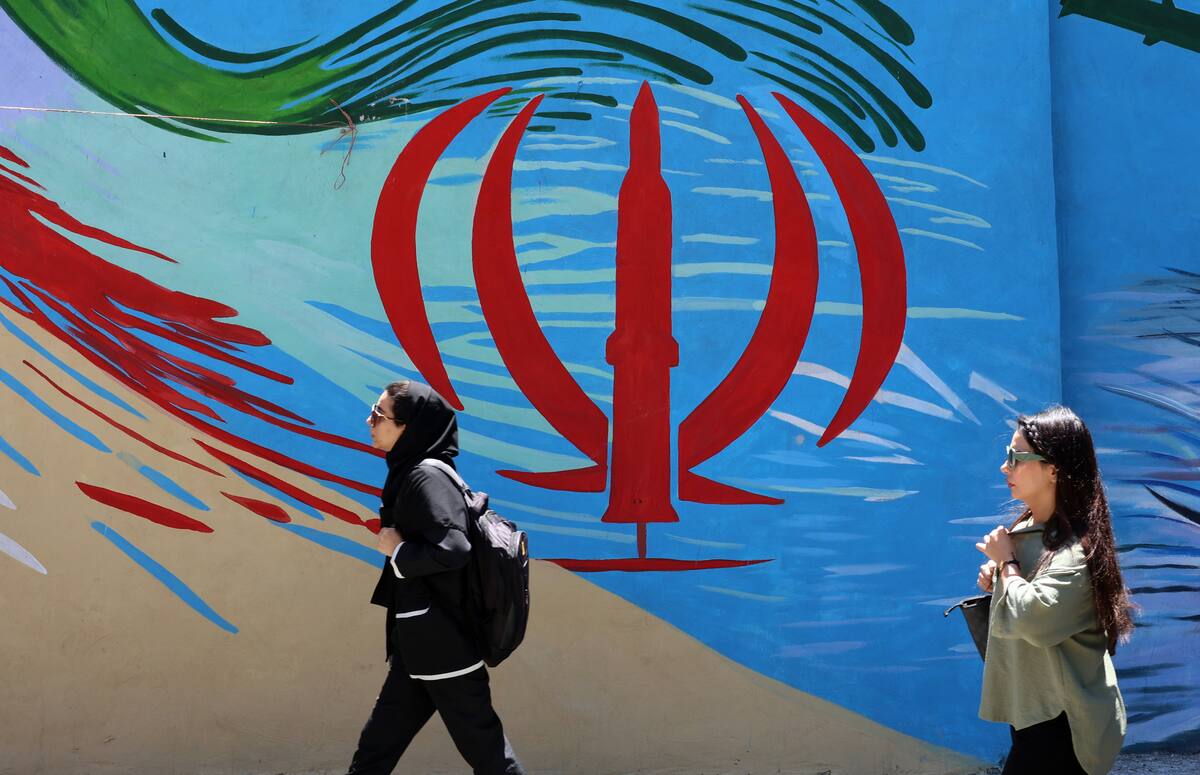 Ciudadanos iraníes pasan junto a un mural con la bandera nacional de Irán en una calle de Teherán, Irán, este lunes. El presidente estadounidense Donald Trump anunció en sus redes sociales que se ha alcanzado un acuerdo con Irán, el cual se firmará el 19 de junio en Suiza. (Suiza, Teherán) EFE/EPA/ABEDIN TAHERKENAREH RESTRICCIONES: Prohibido el acceso a medios de comunicación israelíes/canales de televisión en persa fuera de Irán/Prohibido el acceso a BBC Persian/VOA Persian/Manoto TV/Televisión Internacional de Irán. (Según lo dispuesto por la Dirección General de Medios de Comunicación Extranjeros de Irán)