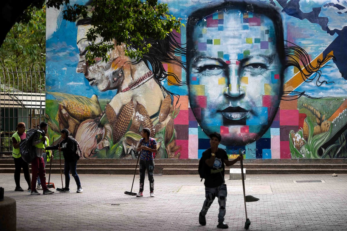 AME1285. CARACAS (VENEZUELA), 02/02/2026.- Personas limpian frente a un mural del fallecido presidente de Venezuela, Hugo Chávez, este lunes, en Caracas (Venezuela). El chavismo cumple 27 años en el poder de Venezuela con su actual líder, Nicolás Maduro, detenido en Estados Unidos, luego de que fuerzas de este país lo capturaran hace casi un mes junto a su esposa, la diputada Cilia Flores, en medio de una serie de ataques en suelo venezolano. EFE/ Ronald Peña R