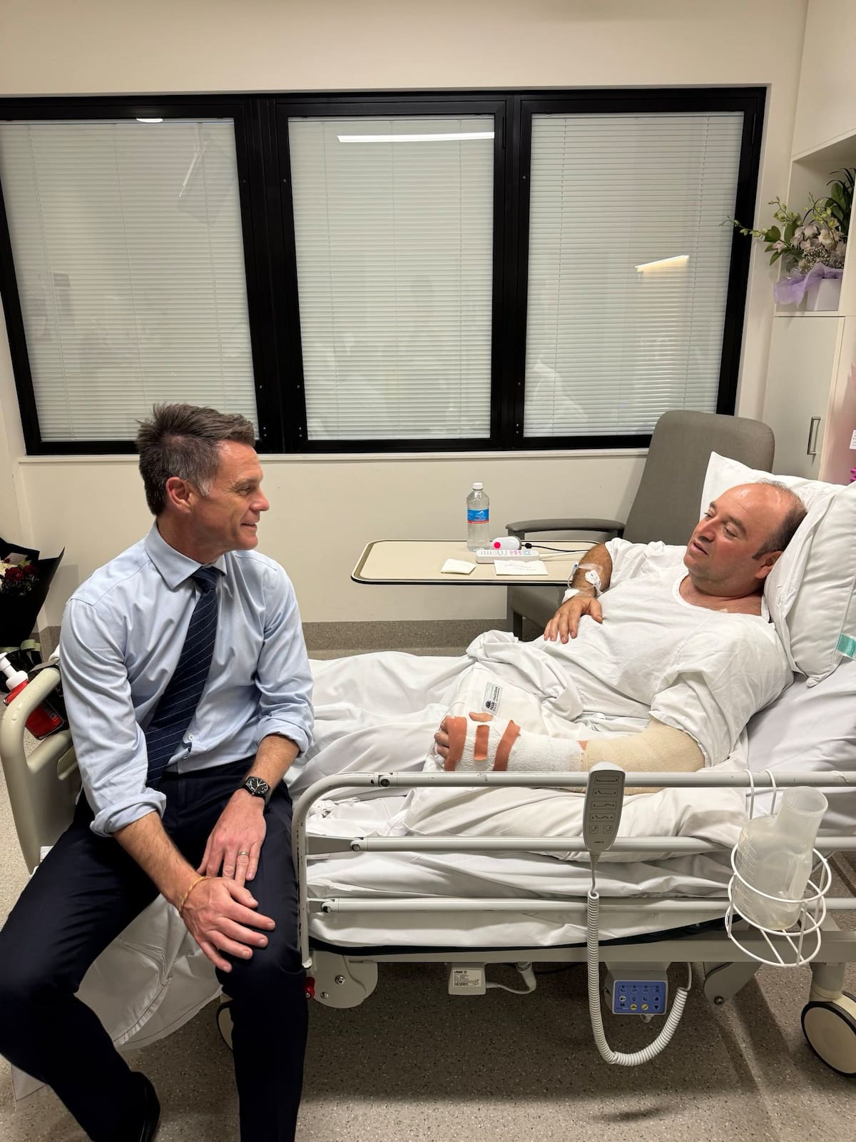 Fotografía publicada en el perfil de X del líder político de Nueva Gales del Sur, Chris Minns, que muestra a Minns (i) visitando en el hospital a Ahmed al Ahmed, el hombre que desarmó a uno de los autores del atentado perpetrado ayer en Sídney. Junto a la fotografía, Minns define a Ahmed como "un héroe de verdad" cuya "increíble valentía sin duda salvó innumerables vidas al desarmar a un terrorista con un enorme riesgo personal". Ahmed, de 43 años, se escondió el domingo detrás de unos vehículos para sorprender a uno de los asaltantes y forcejear con él hasta quitarle con sus propias manos el rifle con el que disparaba a los transeúntes en la popular playa de Bondi. Como consecuencia, Ahmed recibió disparos en el brazo y la mano. EFE/ Chris Minns vía red social X