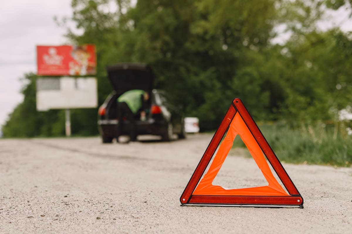 Driver putting warning triangle on asphalt road. Emergency stop concept.