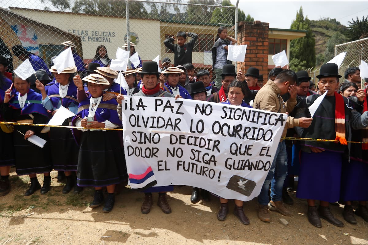 AME4188. SILVIA (COLOMBIA), 22/05/2026.- Indígenas de la comunidad Misak sostienen un cartel durante la llegada de cuerpos de fallecidos este viernes, en Silvia (Colombia). Los enfrentamientos por territorios entre indígenas de los pueblos colombianos Misak y Nasa en el departamento del Cauca (suroeste) han dejado al menos seis muertos y más un centenar de heridos, confirmó el ministro de Defensa, Pedro Sánchez Suárez. EFE/ Ernesto Guzmán Jr