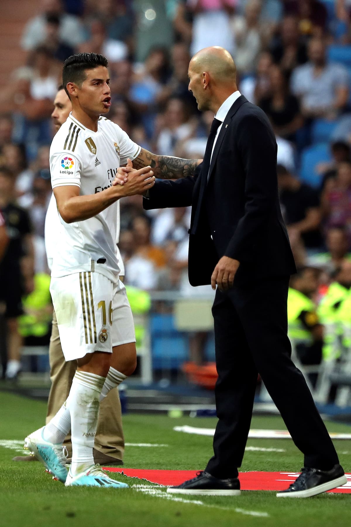 GRAF379. MADRID. 24/08/2019.- El jugador del Real Madrid James Rodríguez (i) saluda a su entrenador Zinedine Zidane (d) tras salir sustituido, en el partido correspondiente a la 2ª Jornada de LaLiga Santander ante el Real Valladolid, disputado en el Estadio Santiago Bernabéu, en Madrid. EFE/Kiko Huesca