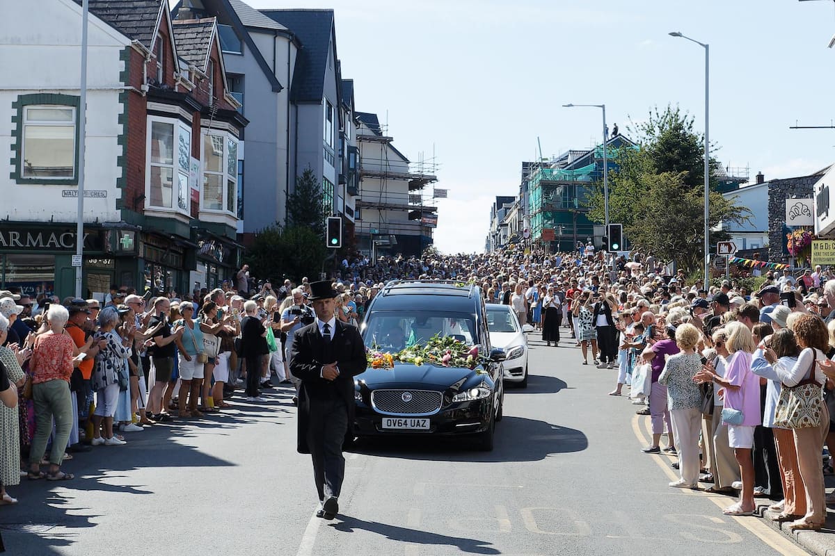 Admiradores rinden homenaje colocando flores sobre la coche fúnebre que transporta a la cantante galesa Bonnie Tyler mientras avanza por Newton Road hacia su casa en Llwynderw, Mumbles, Gales, Gran Bretaña, 15 de agosto de 2026. La cantante galesa falleció en un hospital de Portugal el 8 de julio de 2026, a los 75 años. Está programada una celebración de su vida en Swansea Minster (Iglesia de Santa María) el 17 de agosto de 2026. EFE/EPA/DIMITRIS LEGAKIS