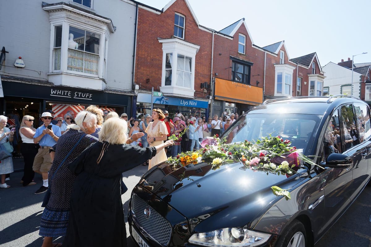 Admiradores rinden homenaje colocando flores sobre la coche fúnebre que transporta a la cantante galesa Bonnie Tyler mientras avanza por Newton Road hacia su casa en Llwynderw, Mumbles, Gales, Gran Bretaña, 15 de agosto de 2026. La cantante galesa falleció en un hospital de Portugal el 8 de julio de 2026, a los 75 años. Está programada una celebración de su vida en Swansea Minster (Iglesia de Santa María) el 17 de agosto de 2026. (Reino Unido) EFE/EPA/DIMITRIS LEGAKIS