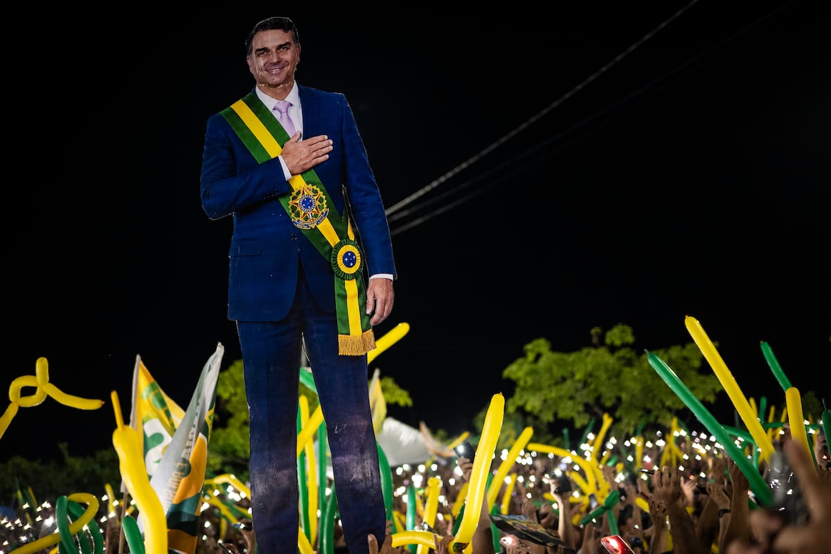 AME7687. MANAOS (BRASIL), 19/10/2026.- Simpatizantes del candidato a la presidencia de Brasil, Flávio Bolsonaro, sostienen una imagen suya durante un acto de campaña llamado "bloquinho 22" este lunes, en Manaos, Amazonas (Brasil). Flávio Bolsonaro defendió la regularización de tierras para ampliar la actividad agropecuaria en la Amazonía, una política impulsada por su padre, el expresidente brasileño Jair Bolsonaro, un defensor de la explotación económica del bioma. EFE/ Raphael Alves