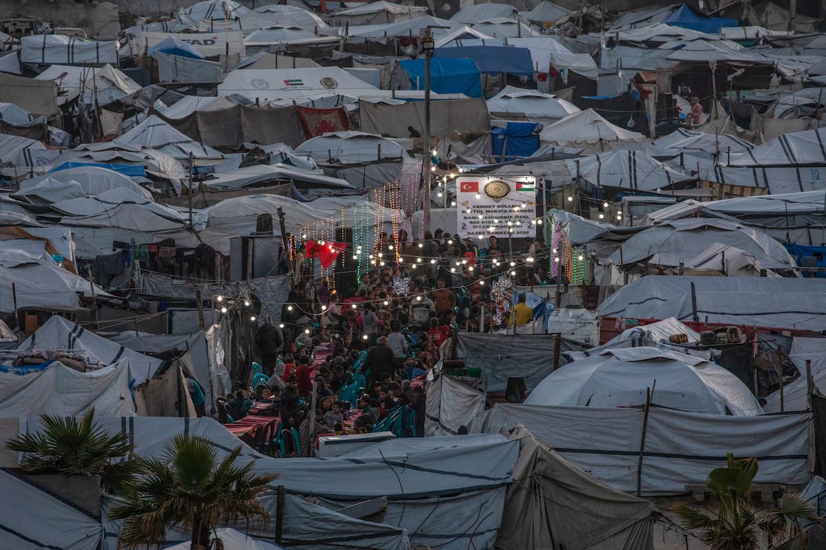 Palestinos desplazados se reúnen entre tiendas de campaña improvisadas para romper el ayuno con una comida iftar juntos durante el mes sagrado de ayuno de Ramadán en el oeste de Gaza. /EFE/MOHAMMED SABER.