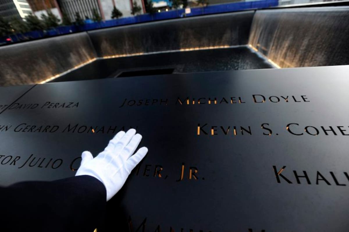 Un policía con guante blanco observa una de las placas conmemorativas a las víctimas en el Memorial 11-S (Foto: EFE)