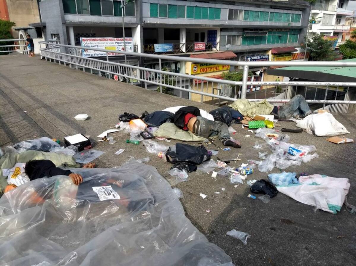 Personas sin hogar duermen entre las basuras dejadas tras la jornada de compras navideñas. (Foto: Daniel Ávila /VANGUARDIA LIBERAL)