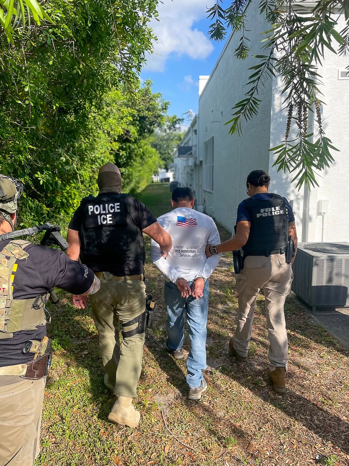 Fotografía divulgada por el Servicio de Control de Inmigración (ICE) donde aparece uno de sus agentes (i) y un policía de Florida (d) mientras llevan a un indocumentado arrestado en Florida (Estados Unidos). Las redadas de inmigración en los lugares de trabajo en EE.UU. se "triplicarán de nuevo" como parte del esfuerzo del Gobierno del presidente de Estados Unidos, Donald Trump, para detener y deportar indocumentados, advirtió este lunes el asesor de seguridad nacional y control migratorio de EE.UU. EFE / VANGUARDIA