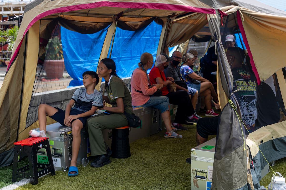 AMDEP8646. CARABALLEDA (VENEZUELA), 14/07/2026.- Personas esperan ser atendidas este lunes, en el hospital de campaña de Japón en Caraballeda (Venezuela). La búsqueda entre los escombros tras el potente doble terremoto en Venezuela ha dejado también víctimas colaterales que han acudido a varios de los 14 hospitales de campaña internacionales instalados en Caracas y la devastada región costera de La Guaira, aledaña a la capital. EFE/ Miguel Gutiérrez