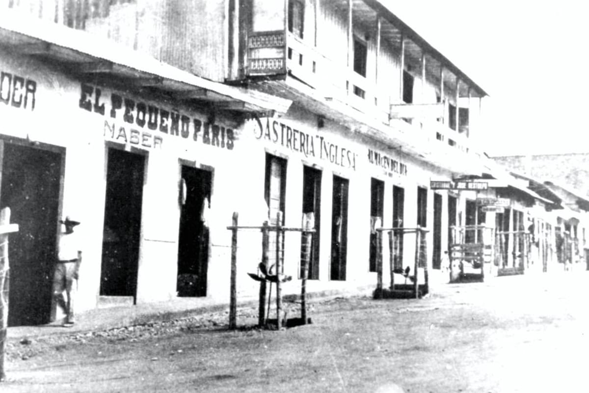 La fotografía capta una parte de la Avenida Santander en 1931. Los nombres de los negocios reflejaban la influencia extranjera en el recién creado municipio de Barrancabermeja, en un sector cercano al muelle. (Foto: Suministrada/VANGUARDIA LIBERAL)