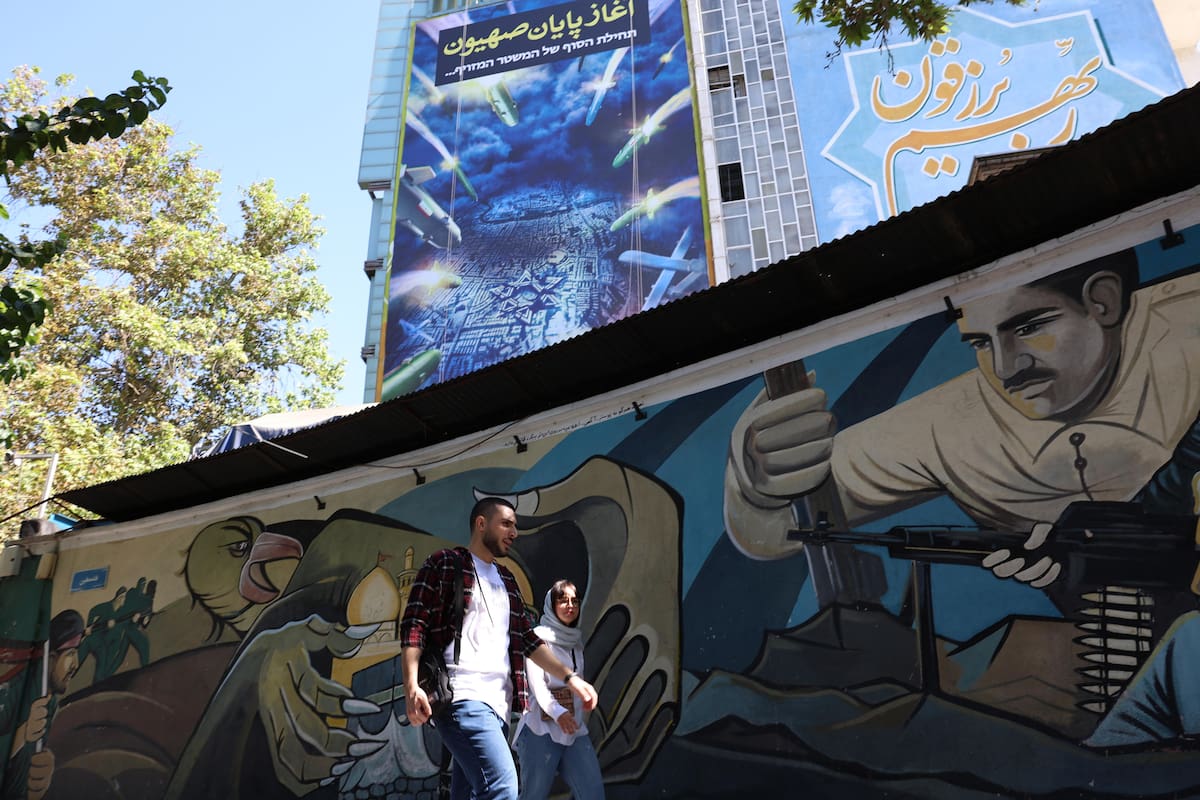 Los iraníes pasan por delante de un cartel antiisraelí que muestra el ataque con misiles de Irán contra Israel y una frase que dice en persa "el comienzo del fin del sionista" en la plaza Palestina de Teherán, Irán, el 03 de octubre de 2024.