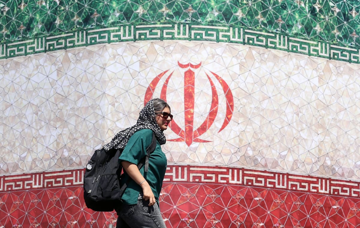 Una mujer iraní pasa junto a una valla publicitaria con la bandera nacional de Irán en la plaza Enqelab de Teherán, Irán.
//EFE/EPA/ABEDIN TAHERKENAREH.