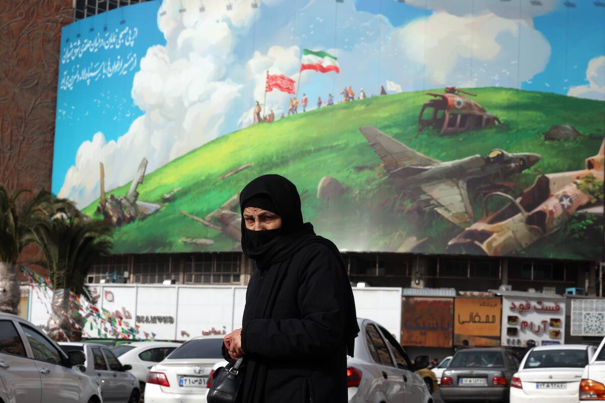Una mujer iraní pasa junto a un cartel antiestadounidense en la plaza Valiasr en Teherán, Irán, el 14 de febrero de 2026. EFE/EPA/ABEDIN TAHERKENAREH