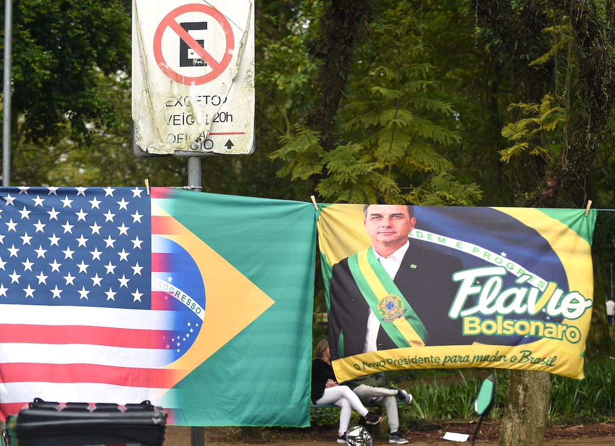 Fotografía que muestra una bandera en apoyo al candidato a la presidencia de Brasil, Flávio Bolsonaro, junto a las banderas de Estados Unidos y de Brasil este domingo, en Porto Alegre (Brasil). La segunda vuelta de las elecciones presidenciales en Brasil transcurre con normalidad, en una jornada pasada por agua en varias regiones del país en la que los ciudadanos decidirán entre Luiz Inácio Lula da Silva y Flávio Bolsonaro al próximo jefe de Estado. EFE/ Ricardo Rímoli