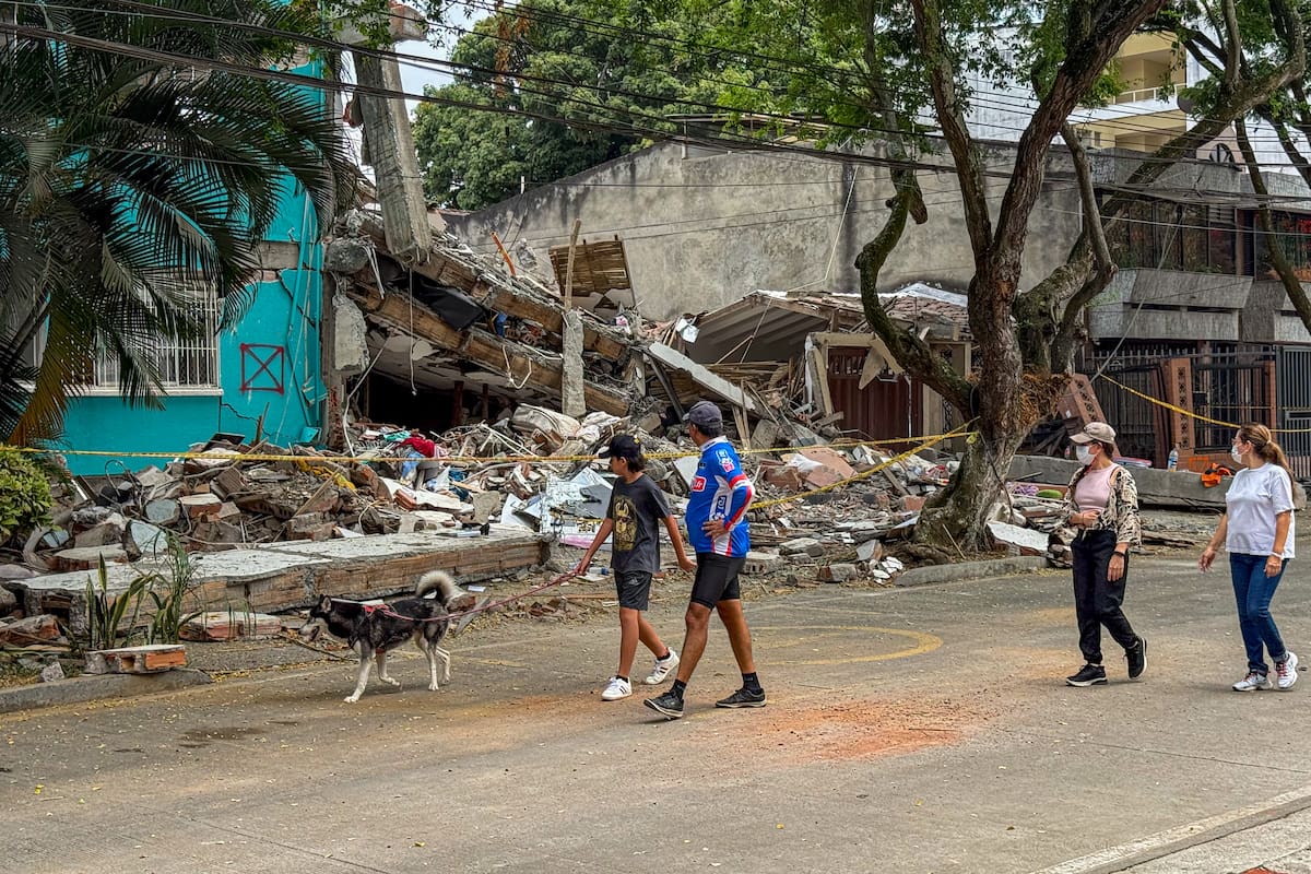 AME9467. CALI (COLOMBIA), 15/08/2026.- Personas caminan este sábado por una calle del barrio Cuarto de Legua, donde vivían las trillizas Saavedra. Dos de ellas murieron junto a sus padres tras el terremoto de magnitud 7,4 ocurrido el pasado lunes, en Cali (Colombia). EFE/Mario Baos