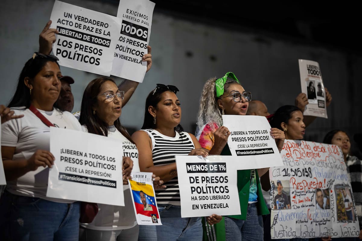 Personas sostienen carteles afuera de El Helicoide, en Caracas (Venezuela). EFE/ Ronald Peña R