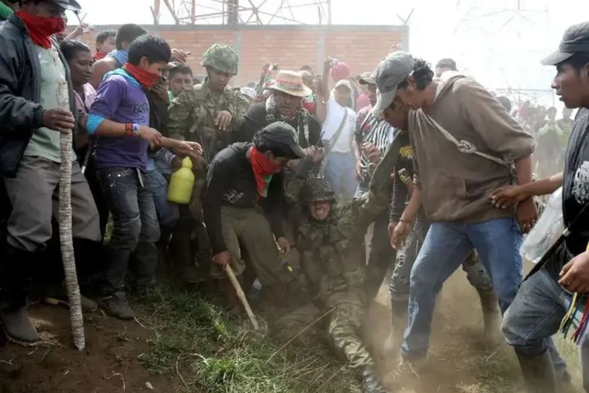 Soldados del Ejército permanecen sentados en el suelo mientras son rodeados por integrantes de comunidades indígenas durante un enfrentamiento ocurrido en Toribío, Cauca, en 2012.