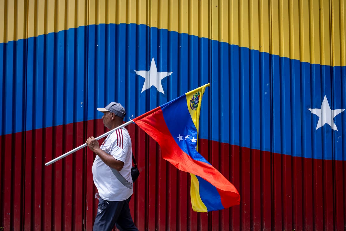 Un hombre camina con la bandera de Venezuela durante una manifestación exigiendo un cronograma electoral y el regreso de la líder y premio nobel de la paz 2025, María Corina Machado, este lunes en Caracas (Venezuela). EFE/ Miguel Gutiérrez