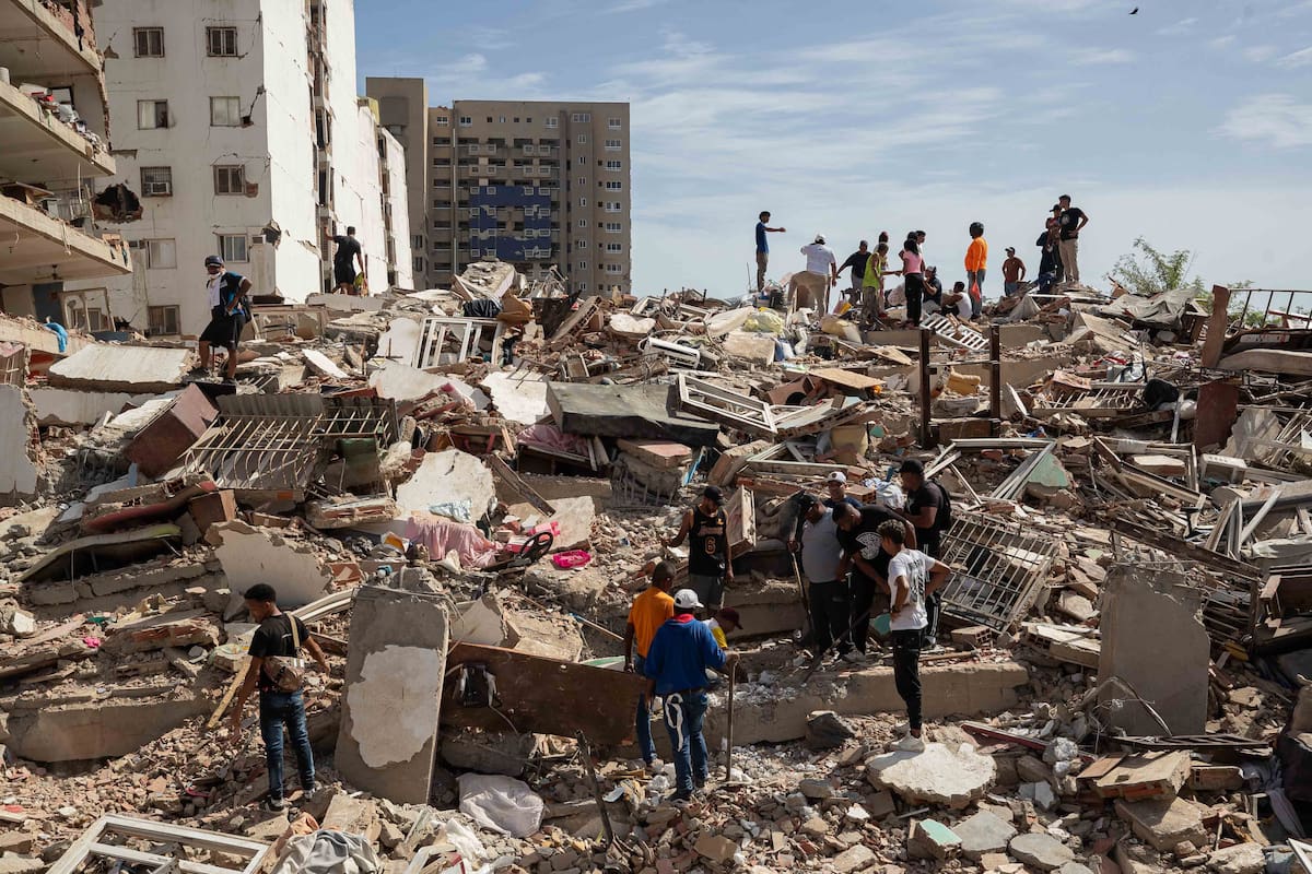 Personas caminan entre escombros de edificios afectado por terremotos este jueves, en Catia La Mar (Venezuela). EFE/ Ronald Peña R.