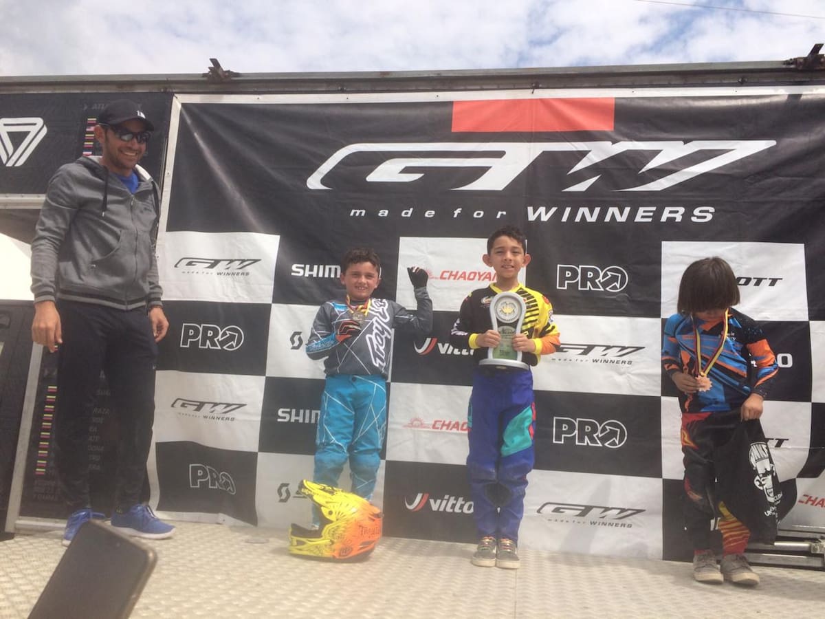 Mattias Serpa Pineda, en el podio de los ganadores con su trofeo de campeón en la mano, bajo la atenta mirada de su papá, el ‘León’, José Rodolfo Serpa Pérez.