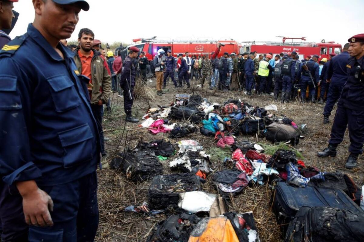 Miembros de los servicios de emergencia rodean parte del equipaje recuperado del avión que se estrelló en el aeropuerto de Katmandú. (Foto: E)