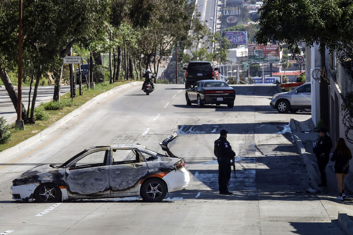 MEX5086. TIJUANA (MÉXICO), 22/02/2026.- Fotografía que muestra un vehículo incendiado este domingo, en Tijuana (México). La Secretaría de la Defensa Nacional de México confirmó el abatimiento de Nemesio Rubén Oseguera Cervantes, alias El Mencho, líder del Cártel Jalisco Nueva Generación (CJNG), lo que ocasionó reacción del grupo criminal realizando bloqueos y quema de vehículos. EFE/Joebeth Terríquez