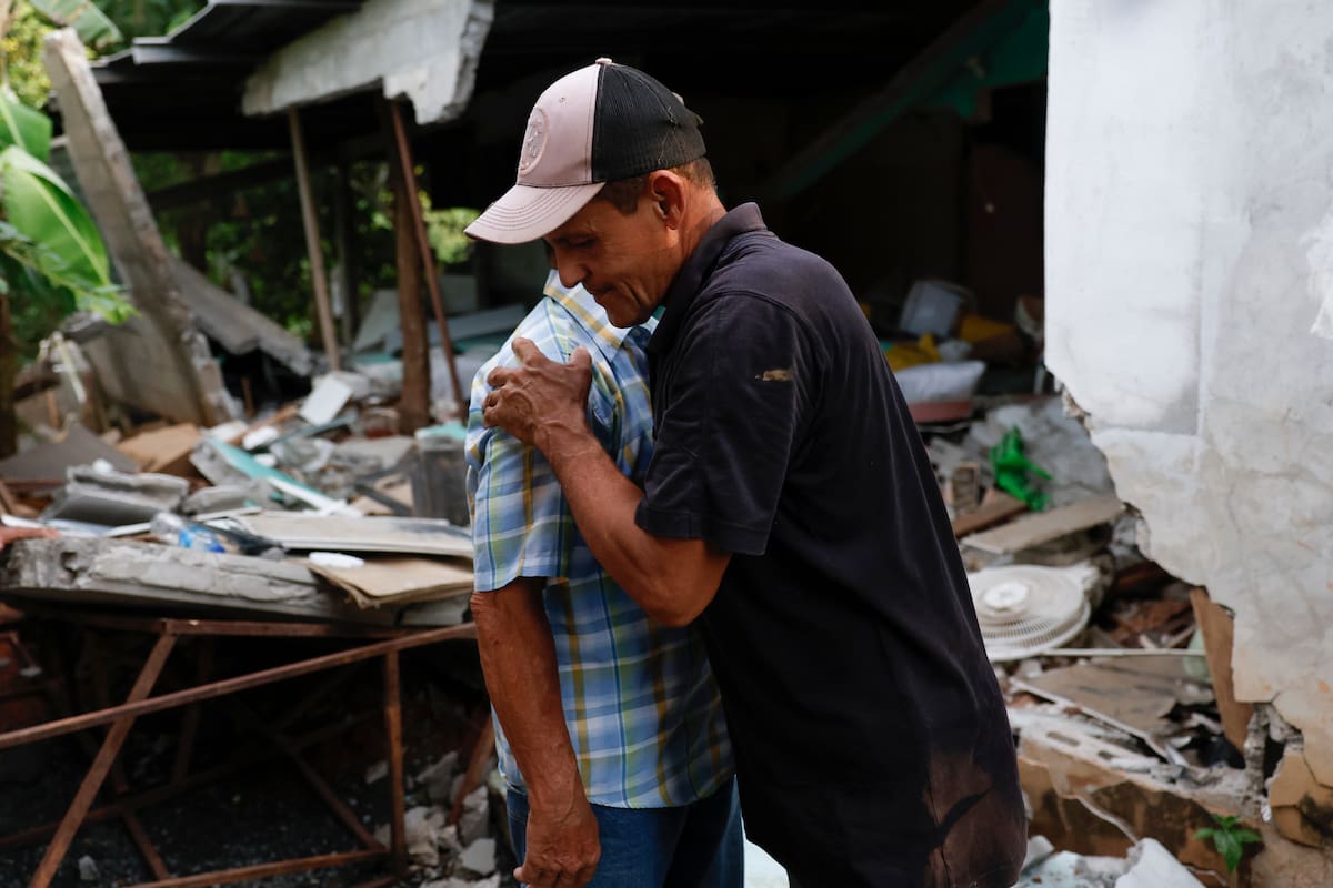 AME6197. MACARACAS (PANAMÁ), 14/10/2026.- Pedro Frías Castillo (i) recibe un abrazo de su hijo Amado en medio de los restos de su casa este miércoles, donde vivía con su esposa Elena Barría Vargas y que fue afectada por el terremoto de magnitud 7,7, en Macaracas, provincia Los Santos (Panamá). Elena, de 68 años, falleció a causas del colapso de un muro en su vivienda y se convierte en la primera muerte oficial relacionada con este sismo que provocó cerca de una treintena de heridos. EFE/ Bienvenido Velasco
