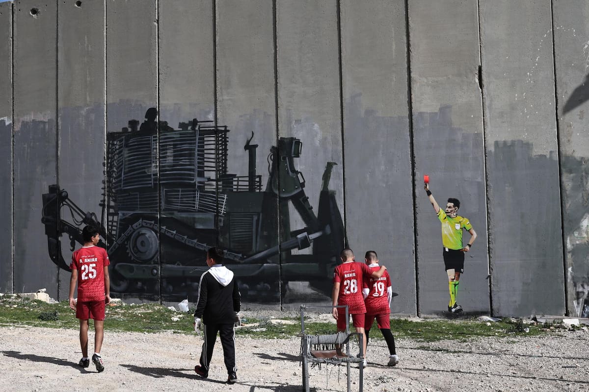 BETHLEHEM (---), 13/02/2026.- Palestinian youth from the Aida refugee camp youth center attend a soccer training at the camp pitch in the West Bank city of Bethlehem, 13 February 2026. Local Palestinian artist Taqi Sbetin, has created a graffiti on the separation wall in protest against the Israeli military order issued for the demolition of the playground in the youth center. (Protestas) EFE/EPA/ATEF SAFADI