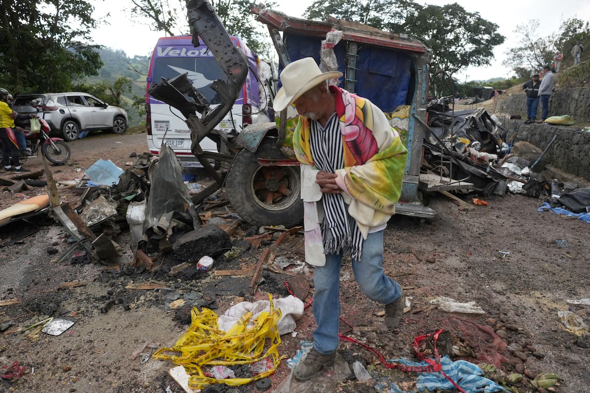 Una persona camina este domingo junto a vehículos destruidos por un atentado ocurrido en la Vía Panamericana en Cajibío (Colombia).